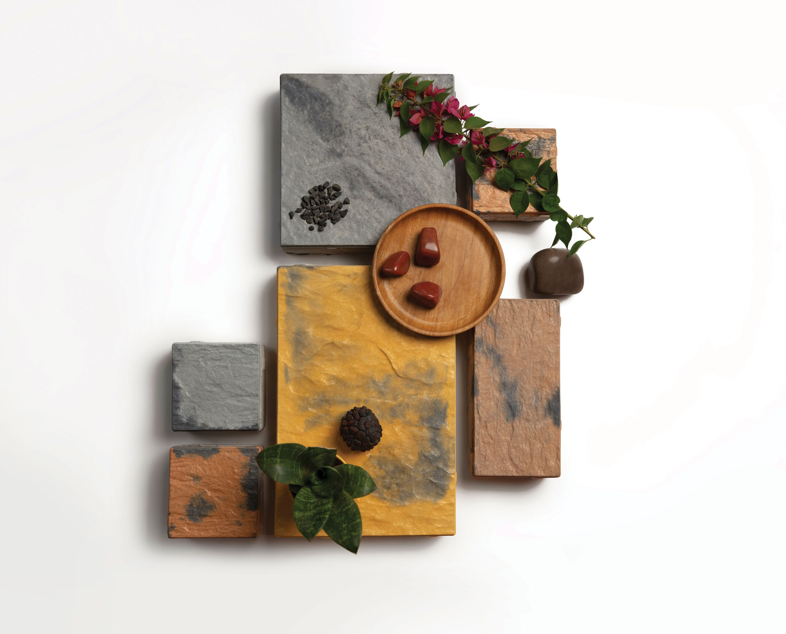 Vinayak Sanitarywares & Tiles: Grey, yellow and brown stone tile samples arranged with green leaves, red flowers and a wooden dish of red stones